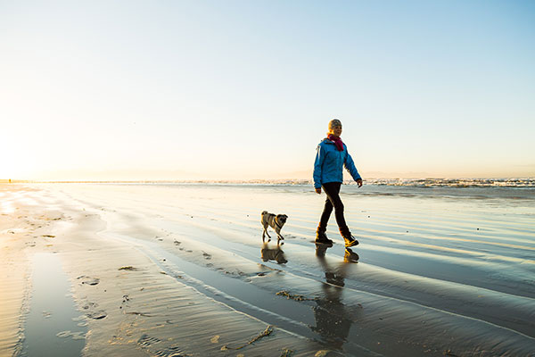woman walking her dog on the beach