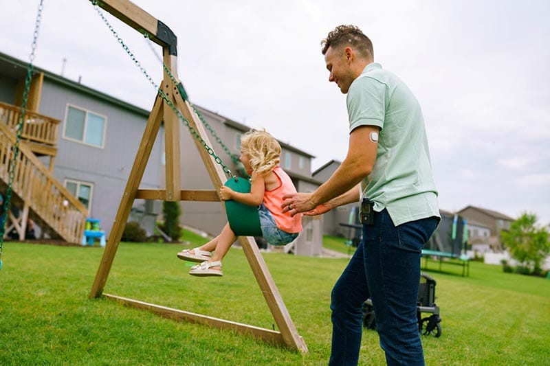 MiniMed Champion pushing daughter on the swing