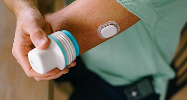 Man applying MiniMed sensor on his arm