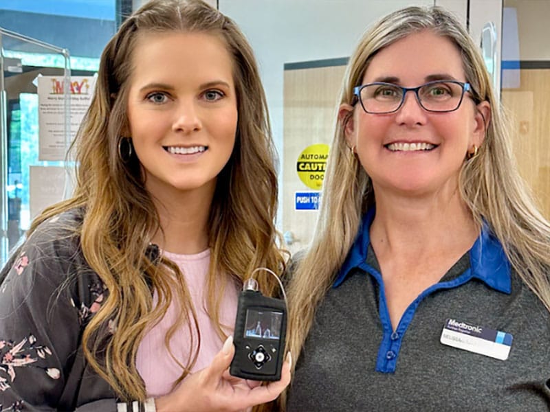 Two women holding MiniMed insulin pump