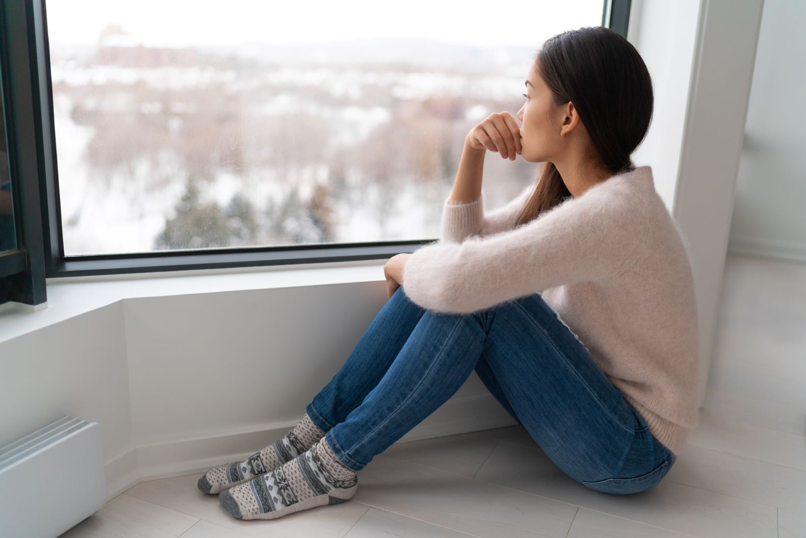 Sad woman looking out window in winter